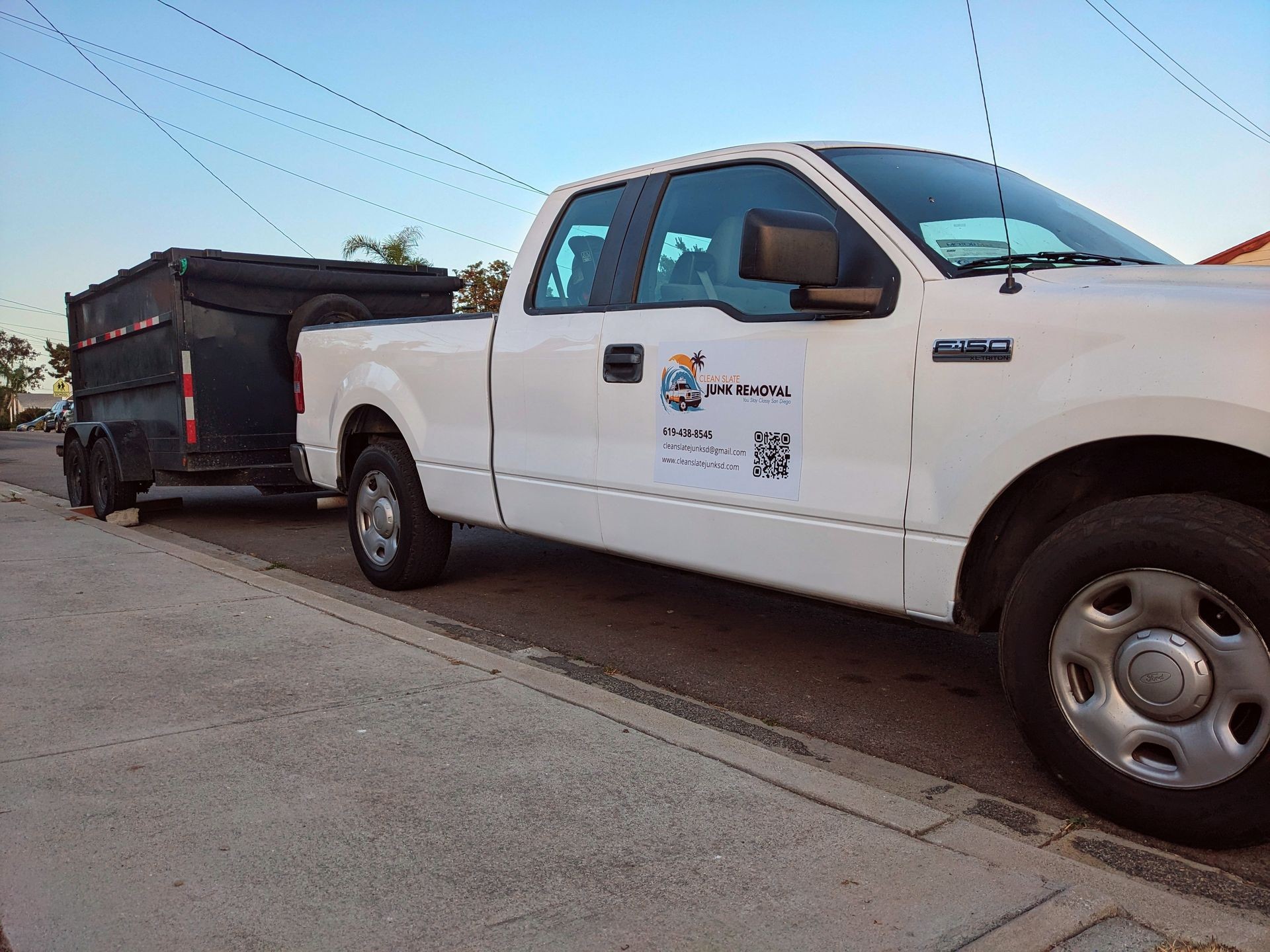 White F150 pickup with a dump trailer behind it